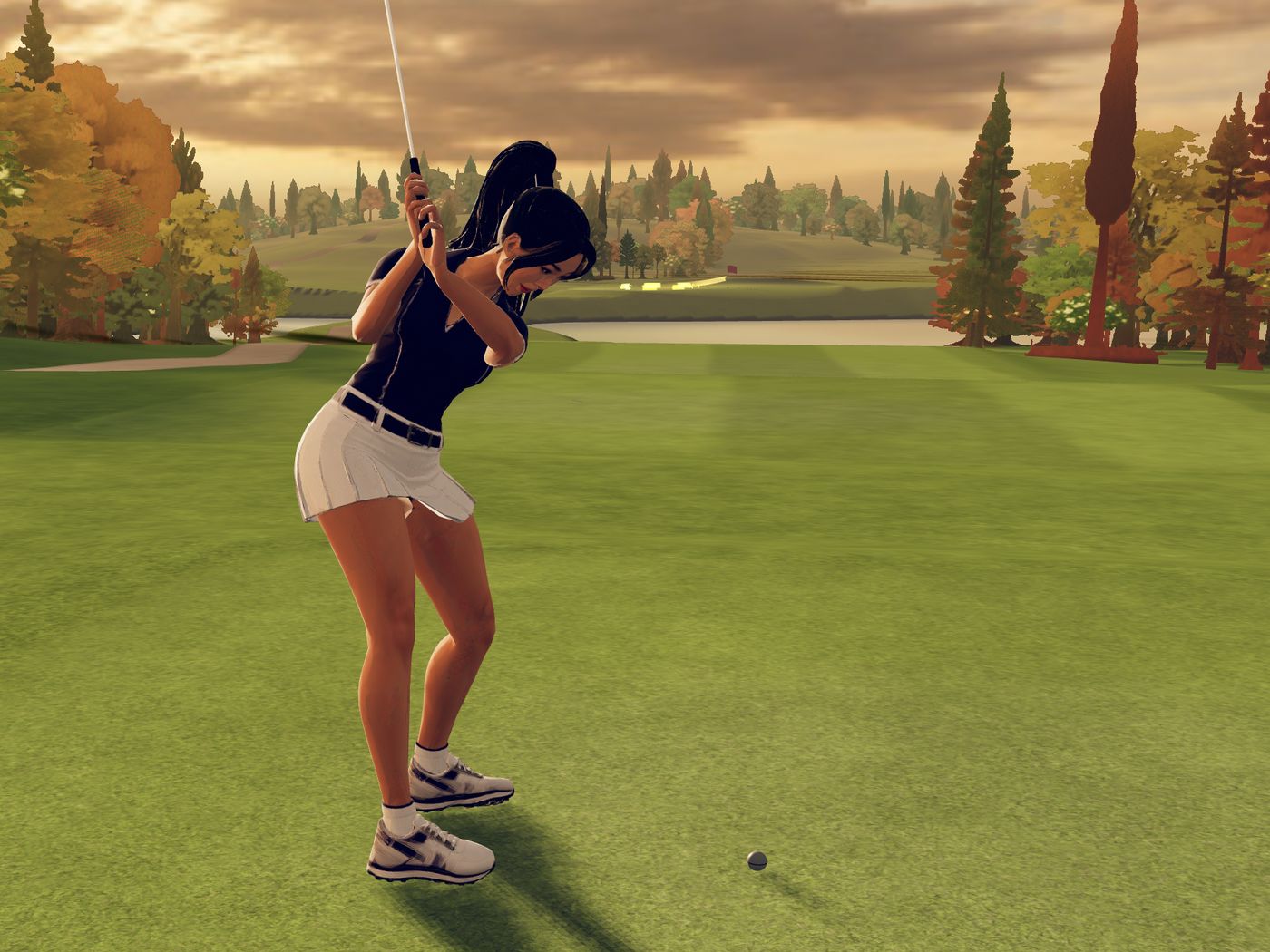 From behind, the golfer in a navy polo and white skirt at the top of her backswing with an iron, the ball at her feet, the pond and the green beyond under a copper sky